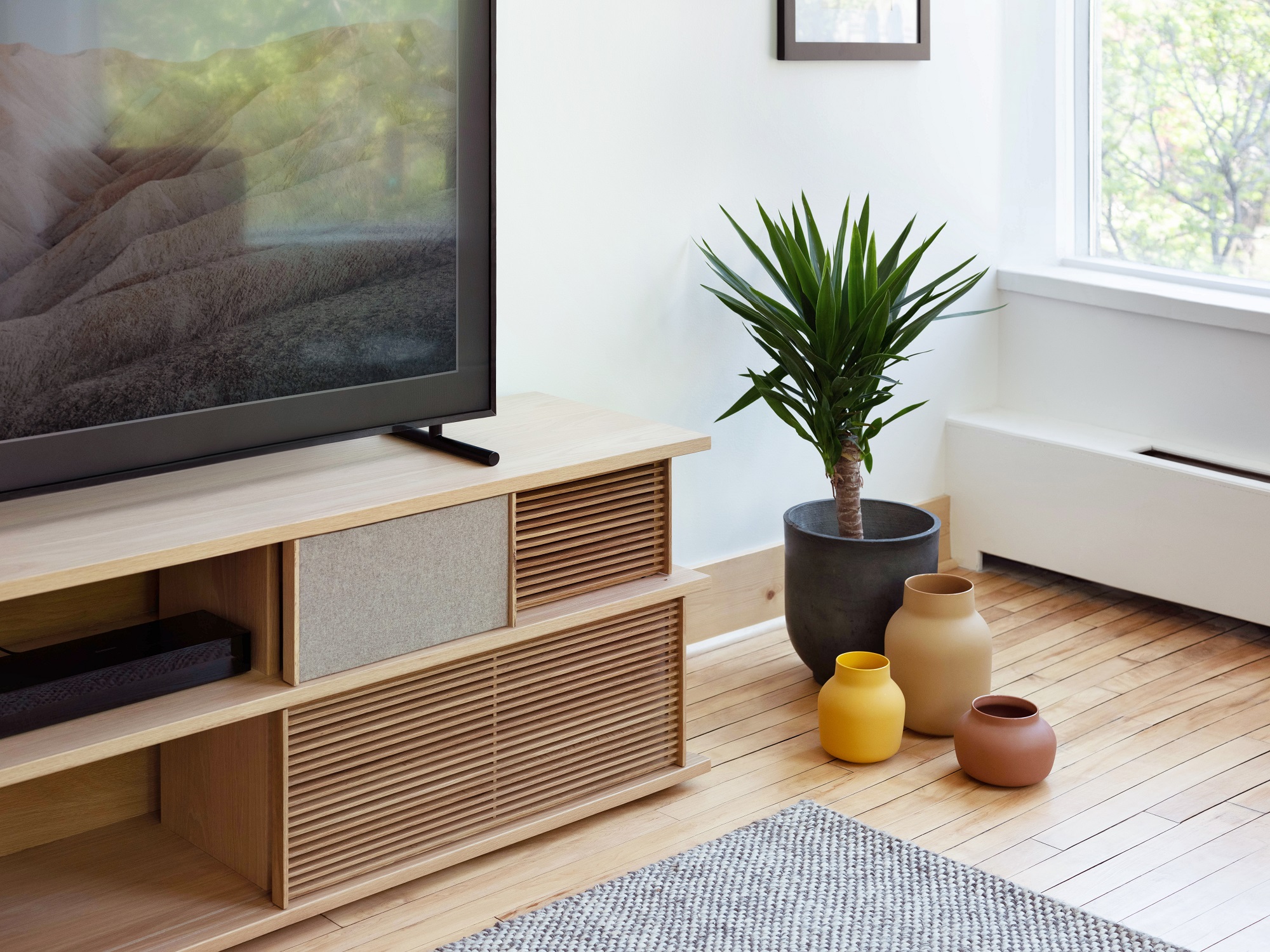 Beige, red, and yellow vases near plant pot and oak media unit